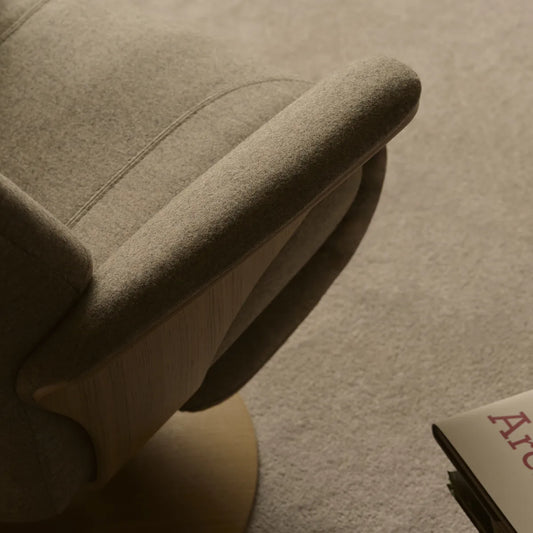Detail van de stoffen bekleding en de houten schijfvoet van een Stressless relaxfauteuil op een tapijt