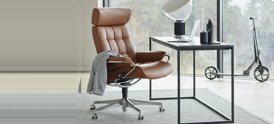 Stressless London high back Office in Paloma Henna-leder op een chromen office-onderstel aan een zwart bureau bij een raam