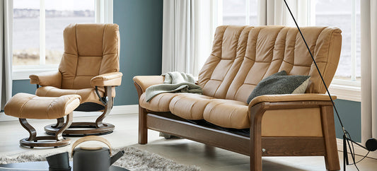Stressless relaxzetel met voetenbank in beige leder naast een bijpassende Stressless Windsor-zitbank in een lichte woonkamer