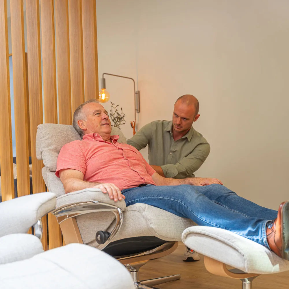 A Stressless Store advisor with paramedical training helps a customer find the right sitting position in a Stressless recliner