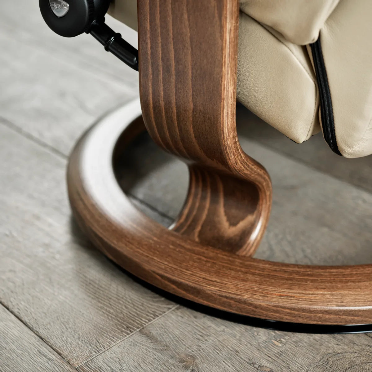 Close-up of the round Classic base in walnut beneath a Stressless Consul in Batick leather