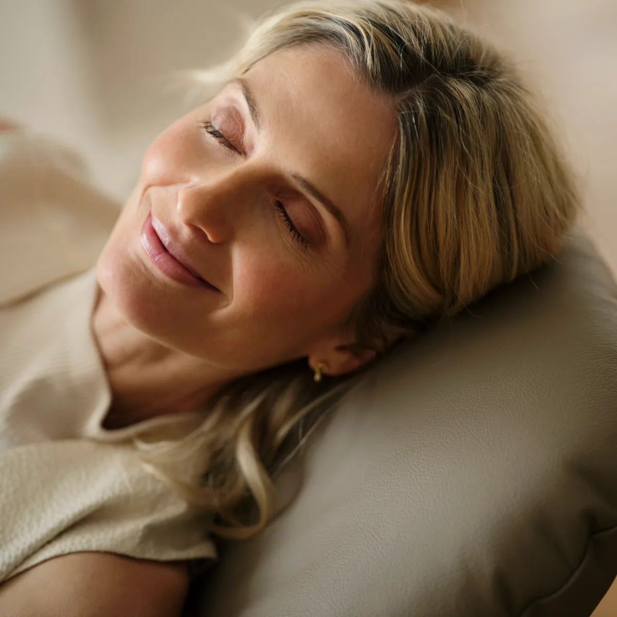 A woman rests her head against the headrest of a Stressless Consul upholstered in Batick Mole leather