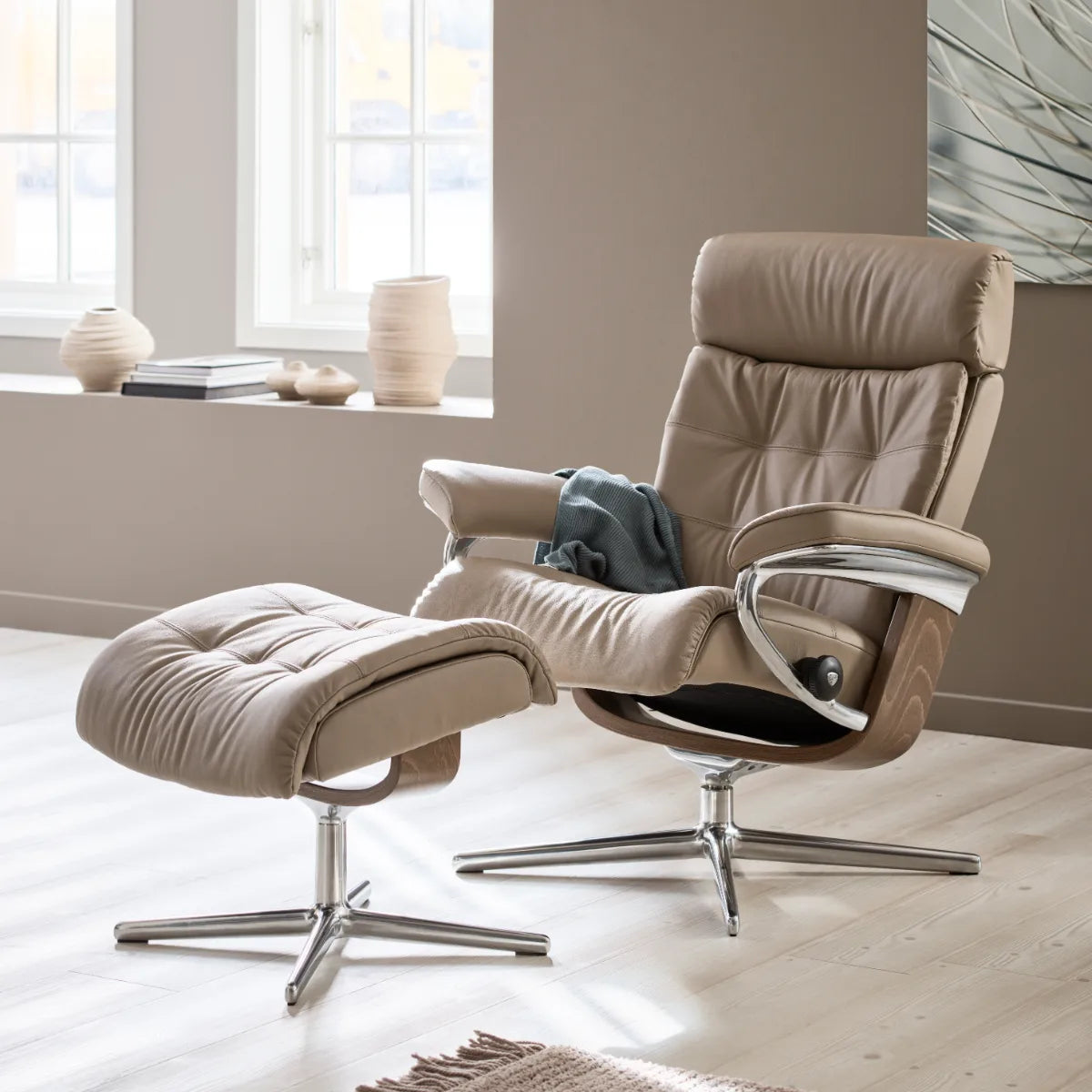 Fauteuil Stressless Erik avec repose-pieds, en cuir Paloma Mushroom, sur un piètement Cross poli avec finition en noyer, dans un salon chaleureux