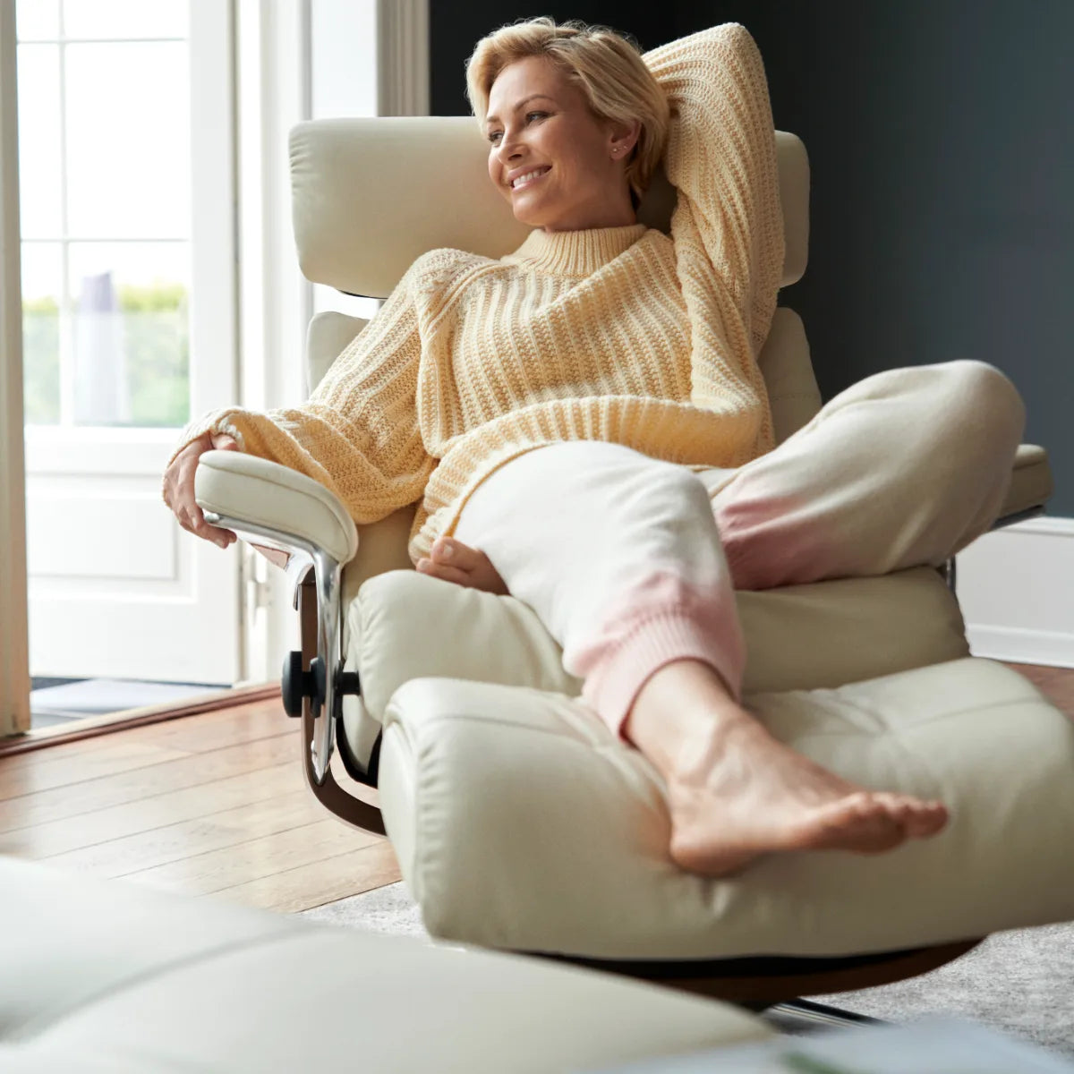 Une femme s'enfonce dans les coussins moelleux d'un Stressless Erik en cuir Paloma Light Grey