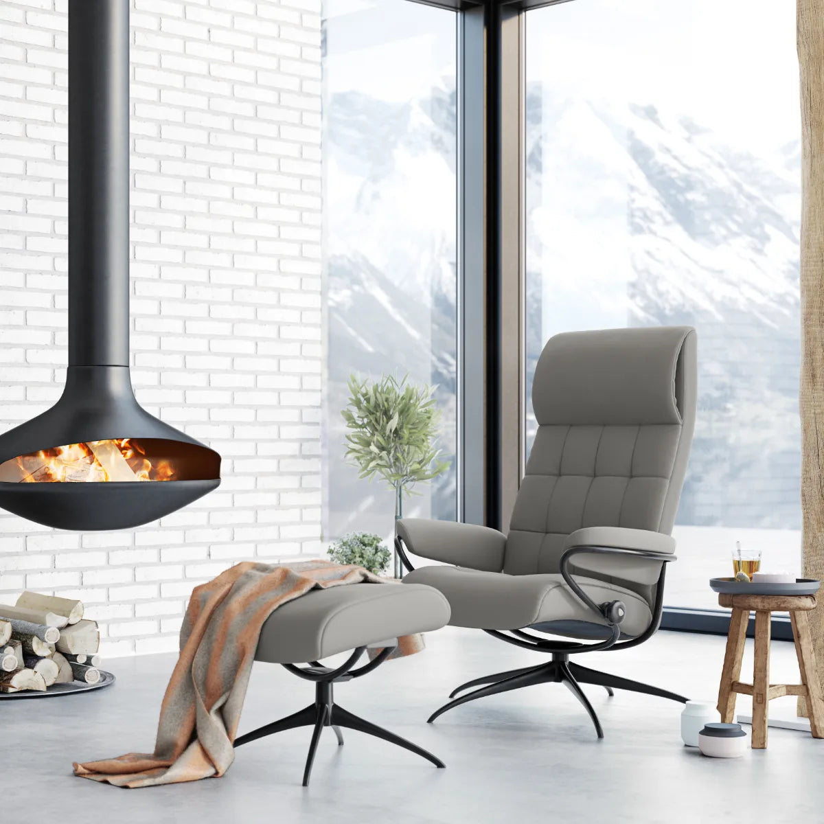 Stressless London met hoge rug in grijs leder op een zwart Star onderstel, naast een hangende open haard
