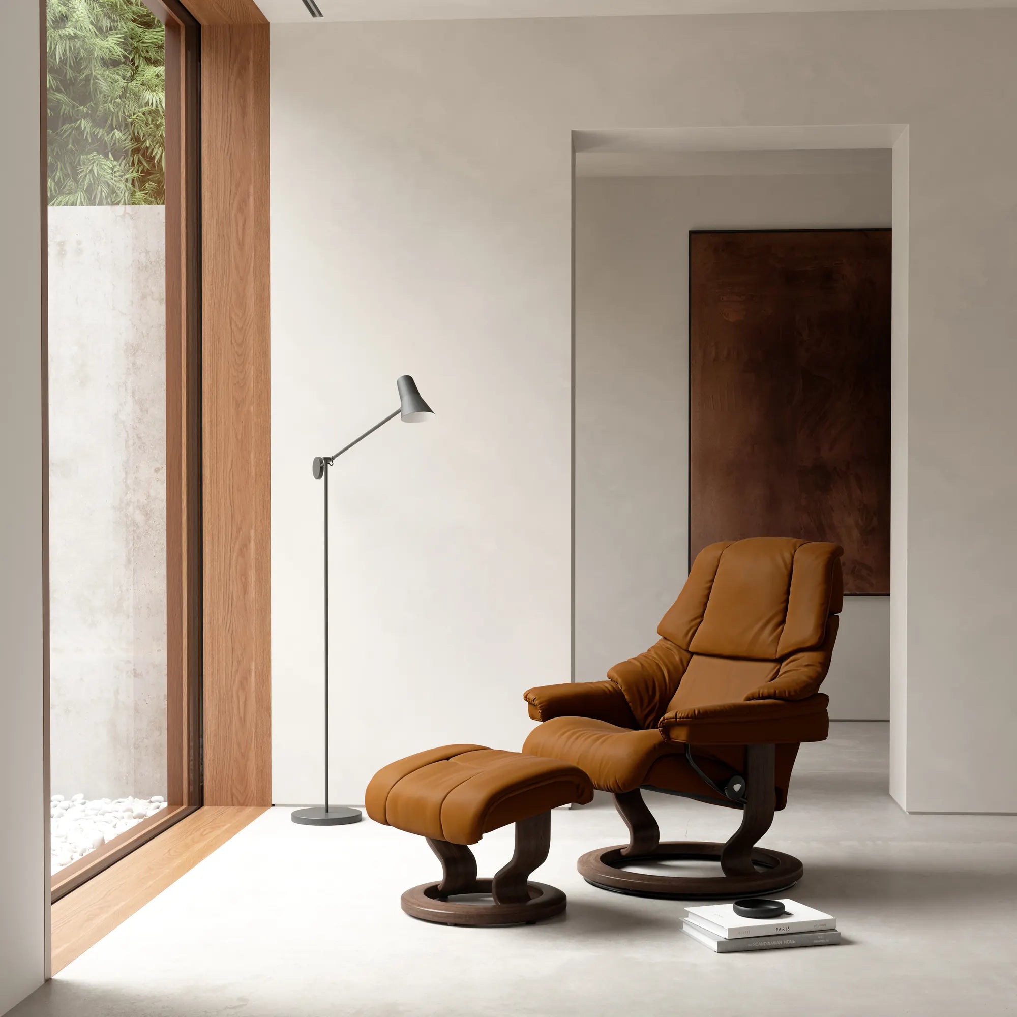 Stressless Reno relaxfauteuil met voetenbank in Batick Warm Brown leder op een Classic onderstel in walnoot, in een lichte woonkamer