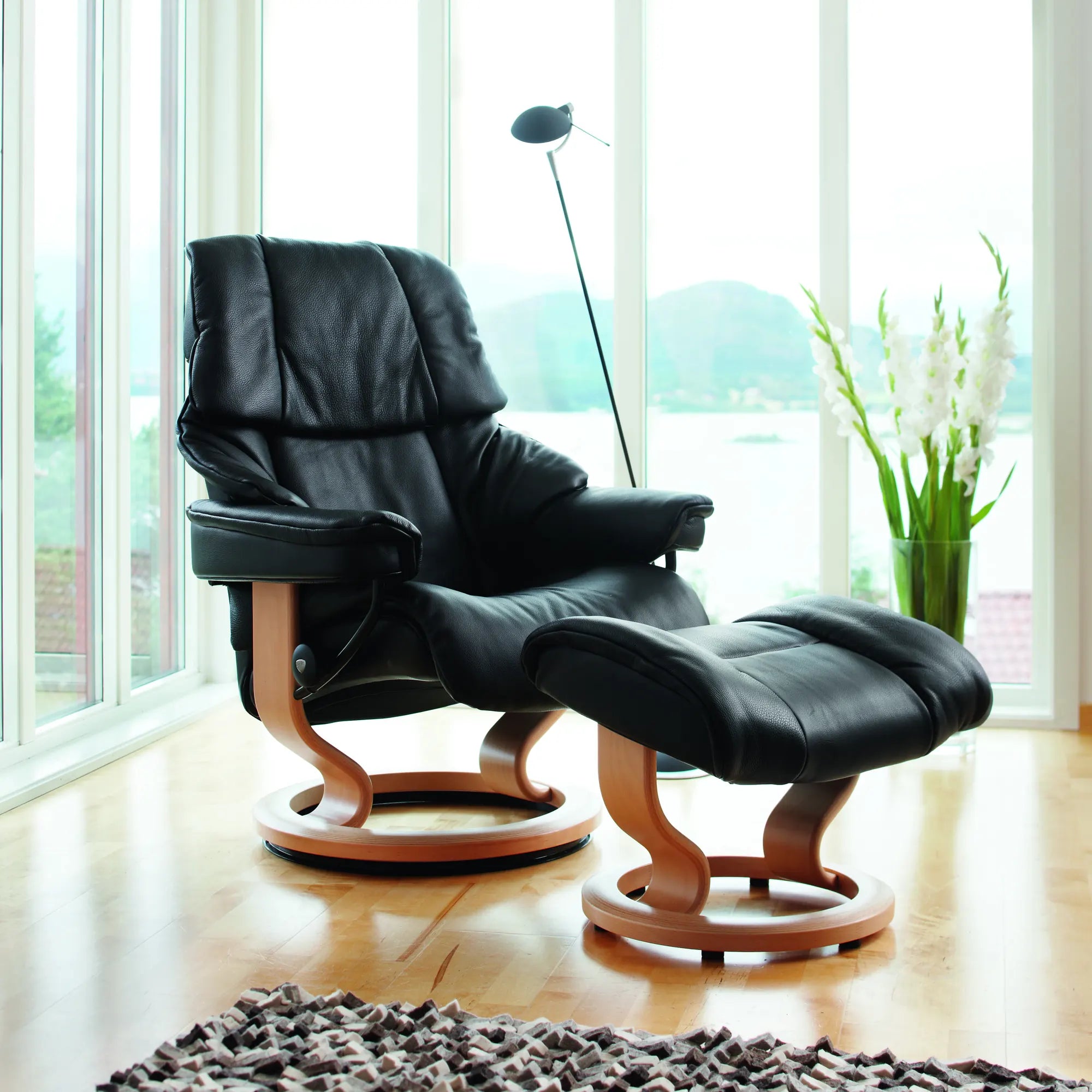 Stressless Reno met voetenbank in Paloma Black leder op een Classic onderstel, bij een groot raam