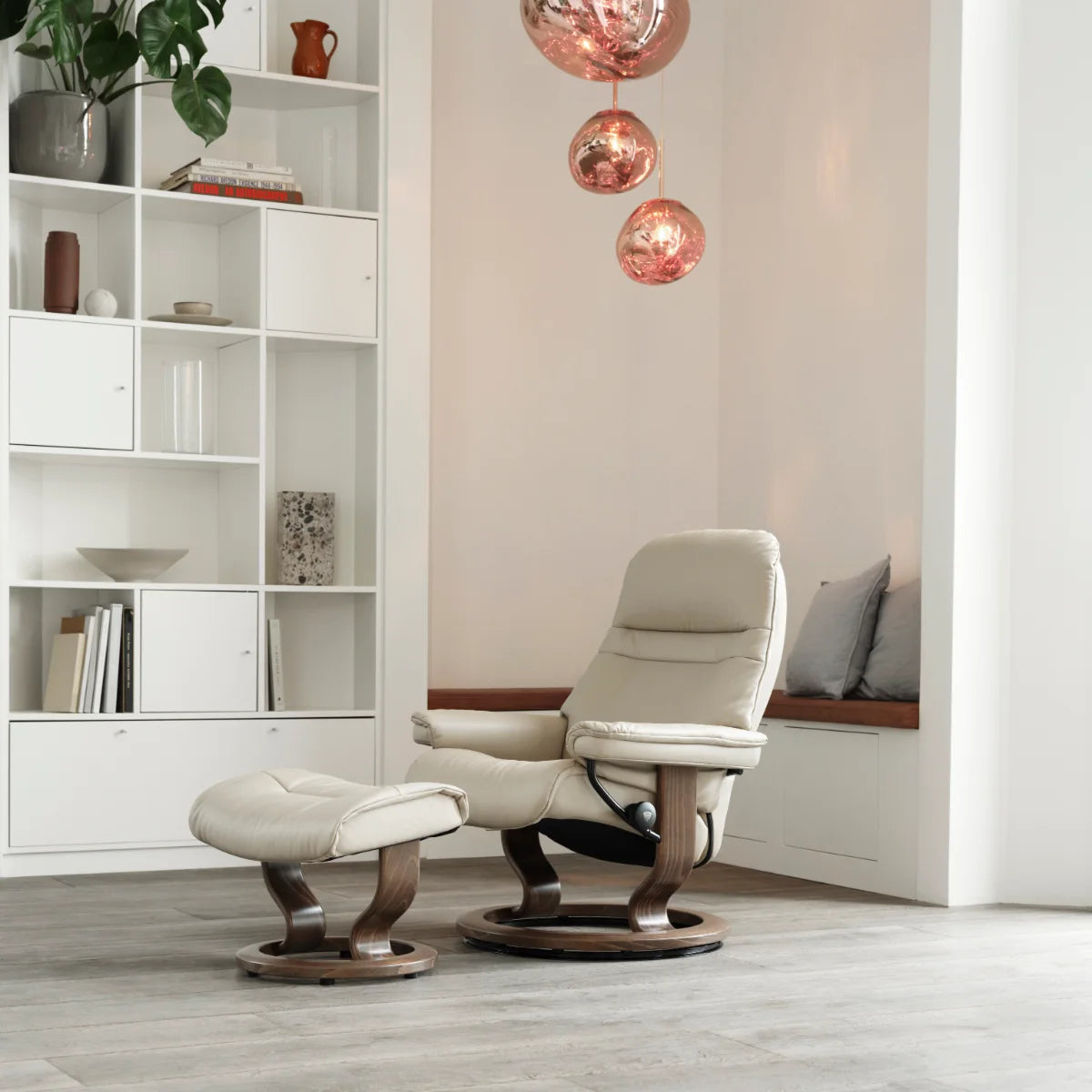Stressless Sunrise met voetenbank in crème Batick leder op een Classic onderstel in walnoot, in een lichte woonkamer met boekenkast