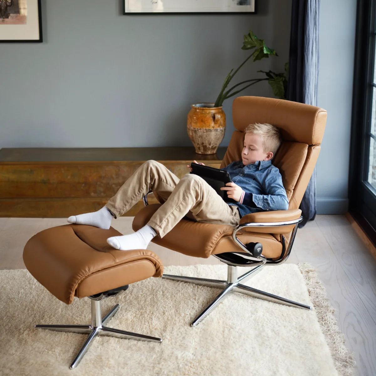 Man leest ontspannen in een Stressless Tokyo met verstelbare hoofdsteun in Batick New Caramel leder met voetenbank
