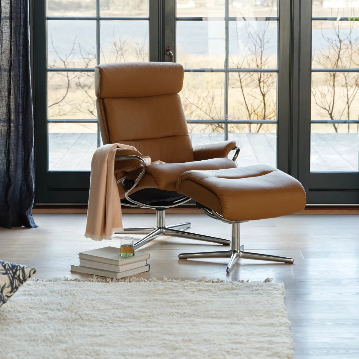 Stressless Tokyo met verstelbare hoofdsteun in Paloma New Cognac leder op een Cross onderstel bij een raam