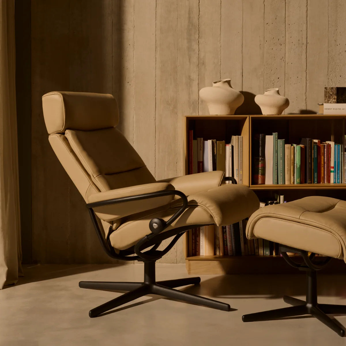 Stressless Tokyo met verstelbare hoofdsteun in Velaro Beige leder op een mat zwart Cross onderstel voor een boekenkast