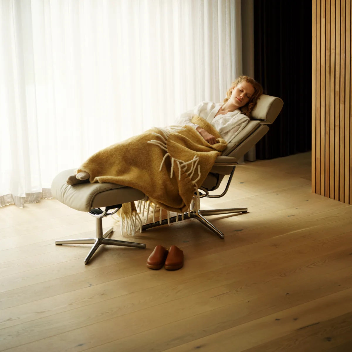 Vrouw ligt ontspannen achterover in een Stressless Tokyo in Paloma Fog leder met de benen op de voetenbank