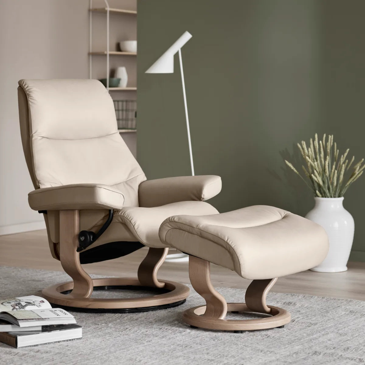 Stressless View in Paloma Fog leder met voetenbank op een Classic onderstel in eiken, in een interieur met groene wand
