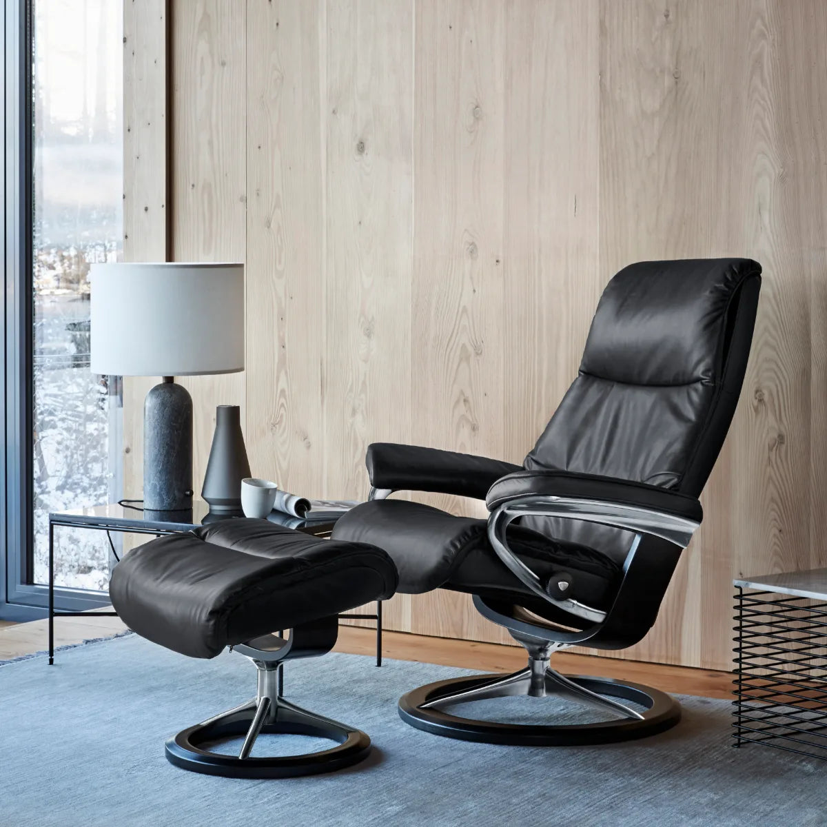 Stressless View Signature in zwart Paloma leder met voetenbank in een leeshoek met staande lamp