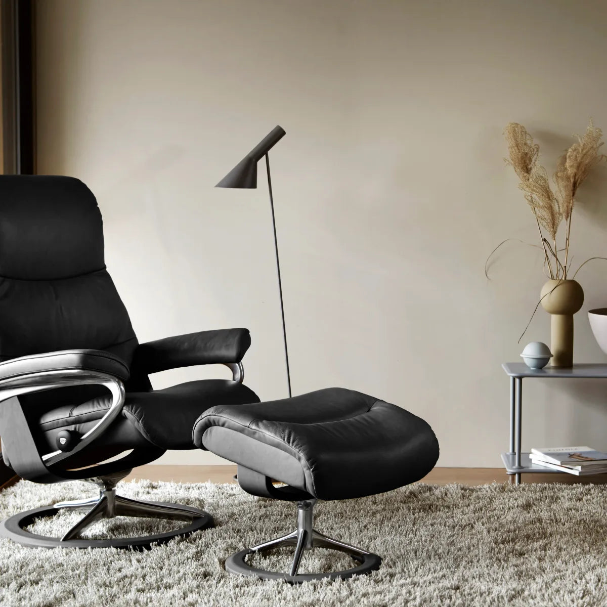 Stressless View Signature in zwart Paloma leder met voetenbank op een tapijt in een rustige woonkamer